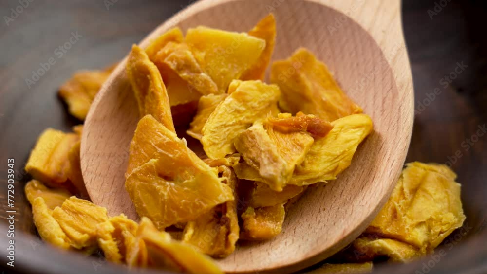 Dried organic mango slices in rustic kitchen dish with wooden spoon close up. Rotation Dried organic mango slices in rustic kitchen dish with wooden spoon close up. Rotation