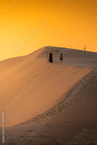 Aerial view of a peasant woman carries a bamboo frame on the shoulder across sand dunes in Ninh Thuan province  Vietnam. It is one of the most beautiful places in Vietnam