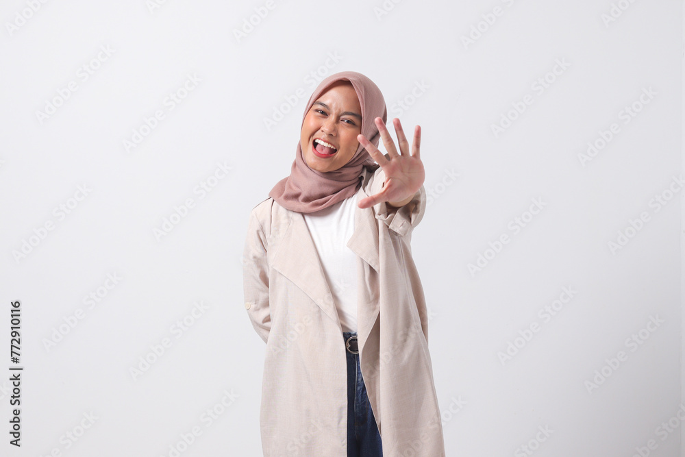 Portrait of excited Asian hijab woman in casual suit showing and pointing up with fingers number five while smiling confident and happy. Businesswoman concept. Isolated image on white background Portrait of excited Asian hijab woman in casual suit showing and pointing up with fingers number five while smiling confident and happy. Businesswoman concept. Isolated image on white background