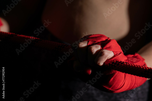A strong fighter is holding a red line ring. Athletic woman focused before the fight.