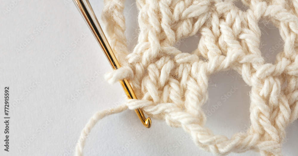 Close-up view of process of hand crocheting lace doily on metal gilded crochet hook from cotton yarn. Empty space for text on white background. Flat lay, copy space, macro Close-up view of process of hand crocheting lace doily on metal gilded crochet hook from cotton yarn. Empty space for text on white background. Flat lay, copy space, macro
