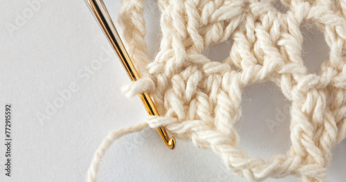 Close-up view of process of hand crocheting lace doily on metal gilded crochet hook from cotton yarn. Empty space for text on white background. Flat lay, copy space, macro