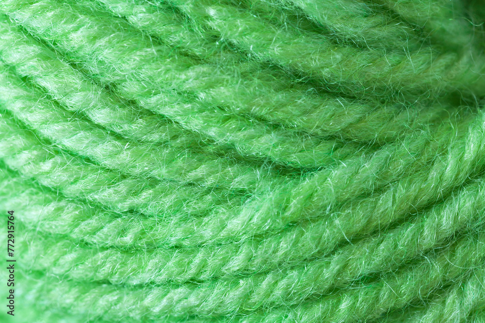 Close-up of a skein of natural woolen green yarn for hand knitting or crocheting. The texture of wool threads wound into a ball. Textile background. Flat lay, macro, top view, copy space Close-up of a skein of natural woolen green yarn for hand knitting or crocheting. The texture of wool threads wound into a ball. Textile background. Flat lay, macro, top view, copy space