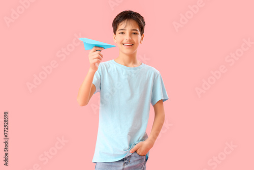 Little boy with paper plane on pink background. Children s Day celebration
