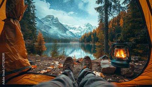 Feet man relaxing in tent with beautiful mountain view. Camping,travel concept. View from the tourist tent to the mountains. Guy in the boots lies on the rug