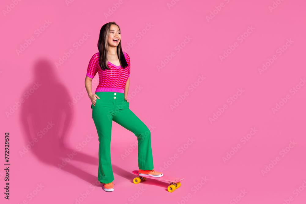 Full length photo of funky impressed lady dressed knitted shirt riding skate board looking empty space isolated pink color background Full length photo of funky impressed lady dressed knitted shirt riding skate board looking empty space isolated pink color background