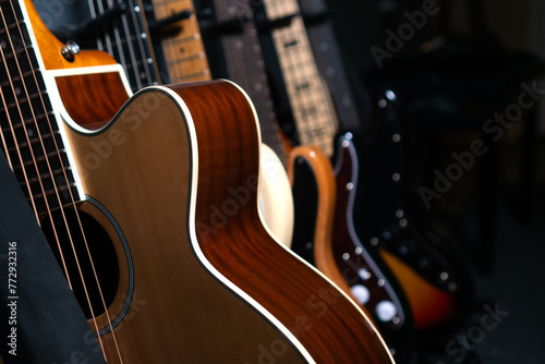 Fotografie Close-up of beautiful guitars standing in a row near the wall in a music studio or in a store, selective focus