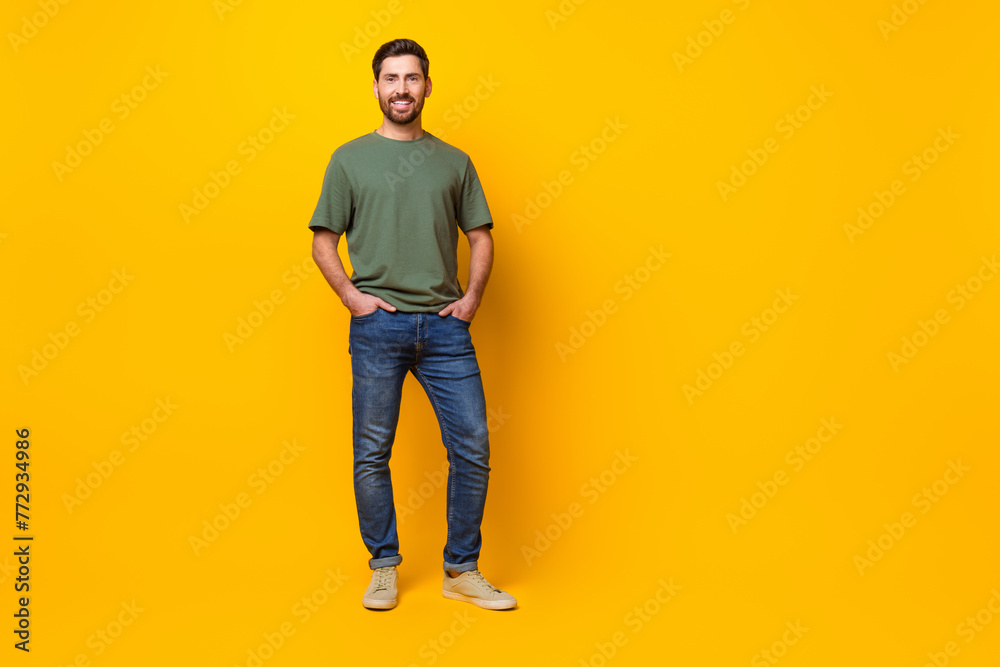 Full length photo of cheerful good mood man wear khaki t-shirt empty space isolated yellow color background Full length photo of cheerful good mood man wear khaki t-shirt empty space isolated yellow color background