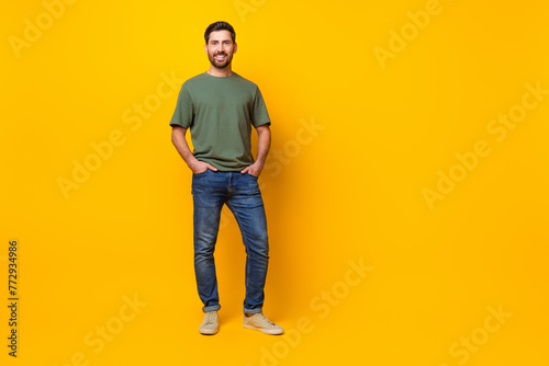 Full length photo of cheerful good mood man wear khaki t-shirt empty space isolated yellow color background
