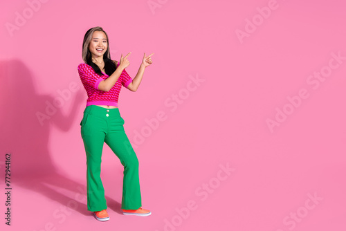 Full length photo of impressed funky lady dressed knitted shirt showing two fingers emtpy space isolated pink color background © deagreez