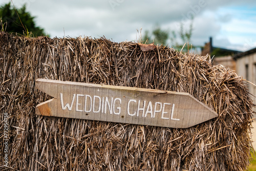 Wedding Chapel wooden sign post on a hay bale. Rustic farm wedding barn