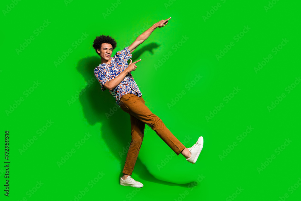 Full length photo of cool guy in jamaican shirt point fingers novelty blink eye cool macho invites party isolated on green color background Full length photo of cool guy in jamaican shirt point fingers novelty blink eye cool macho invites party isolated on green color background