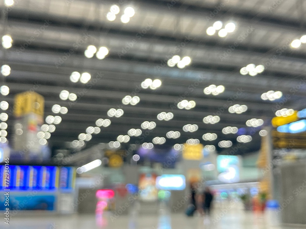 Fototapeta premium blurred photography of the terminal hall at the airport where travellers walk and bokeh of light bulbs on the ceiling