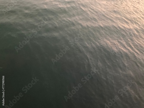 the smooth waves on the black sea surface when the sunset shines above it, using for background