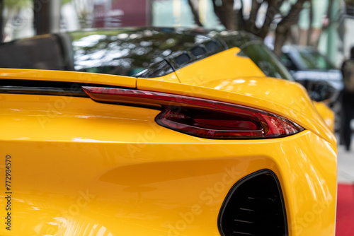 Streamlined rear bumper with elegant stop lights of expensive yellow car. Exterior surface covered with glossy plastic creating downforce while driving allowing to reach high speeds © port-o