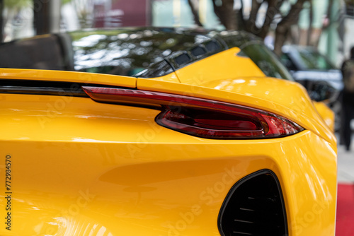 Streamlined rear bumper with elegant stop lights of expensive yellow car. Exterior surface covered with glossy plastic creating downforce while driving allowing to reach high speeds