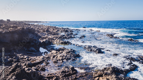 Panoramic view of Atlantic Ocean in a sunny day with calm sea and small waves crashing against the rocks, south of Tenerife, Canary Islands.