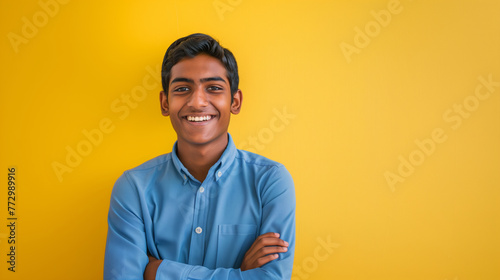 Smiling young Indian male in a blue shirt on a yellow backdrop photo
