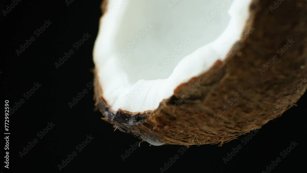 Coconut water juice dripping from half of a coconut on black background slow motion. Coconut water juice dripping from half of a coconut on black background slow motion.