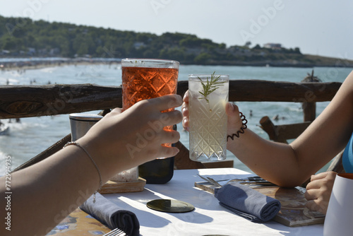 brindisi tra amici con cocktail colorati in un bar all'aperto in riva al mare photo