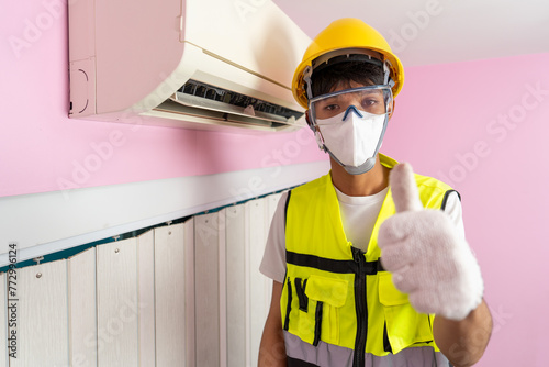 Asian male worker provides cleaning services for air conditioners installed in a home.