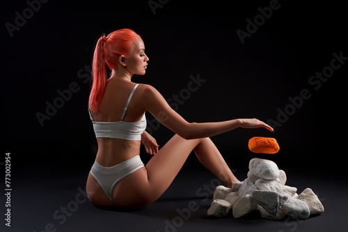 Graceful woman sitting on the floor and making stone levitate