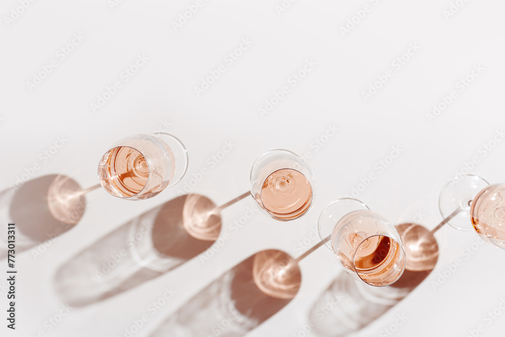 Set of glasses of rose wine at wine tasting, Minimal trend concept. Top view crystal wineglass standing at sunlight, shadow and sun glare, beige pink colored, alcohol drink background, copyspace - obrazy, fototapety, plakaty 