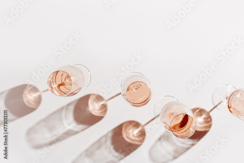 Set of glasses of rose wine at wine tasting, Minimal trend concept. Top view crystal wineglass standing at sunlight, shadow and sun glare, beige pink colored, alcohol drink background, copyspace