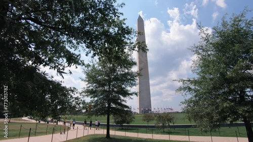 Shot of the Washington Monument and tourists walking in the park around, the Washington monument was build in honor of the US first president G. Washington.