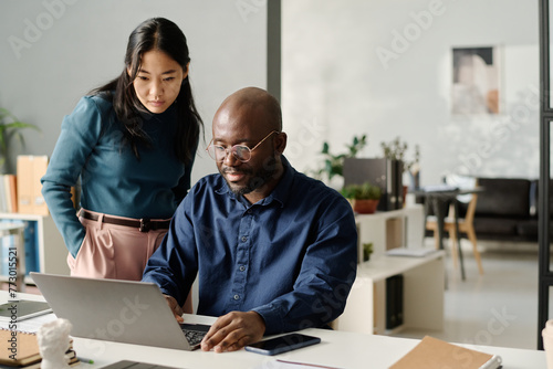 Asian Woman And Black Man Looking At Laptop Screen
