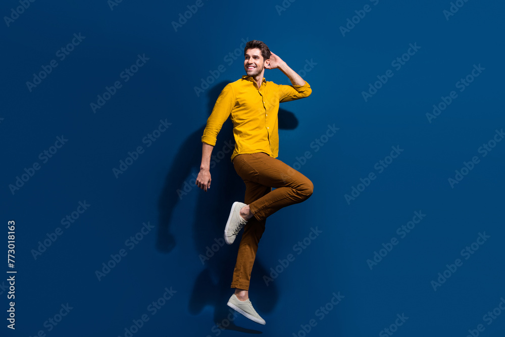 Full body photo of handsome young guy jumping dance discotheque wear trendy yellow outfit isolated on dark blue color background
