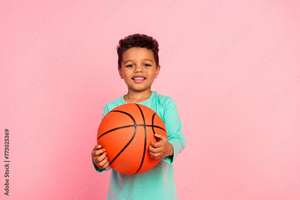 Photo portrait of cute little boy play basketball game wear trendy aquamarine clothes isolated on pink color background Photo portrait of cute little boy play basketball game wear trendy aquamarine clothes isolated on pink color background