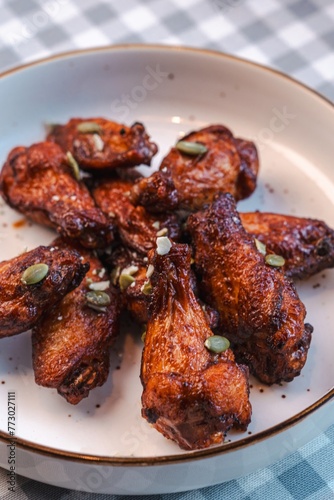 Buffalo wings sprinkled with nuts on a checkered tablecloth