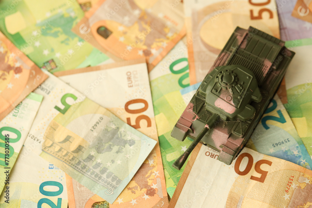 Many euro banknotes and tank. Lot of bills of European union currency and green tank close up