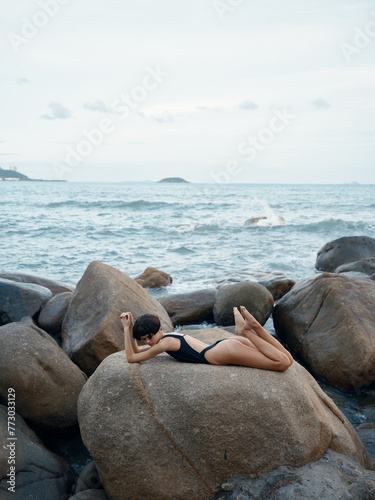 Sensual Summer Beauty: Attractive Woman in Sexy Swimwear Posing on Beach Rocks.
