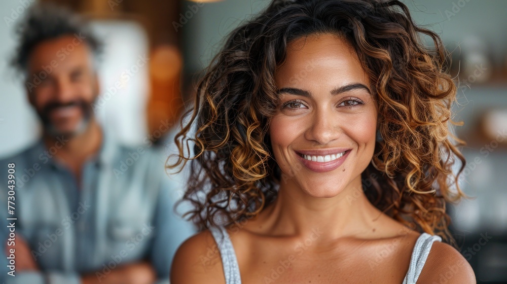 A woman with curly hair smiles at the camera