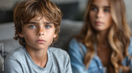 A woman is seated next to a boy on a couch