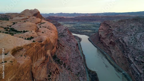 aerial of a canyon near Moab, Utah with Colorado river with red orange sandstone rocks buttes in light of sunset. popular tourist destination. View from height point photo