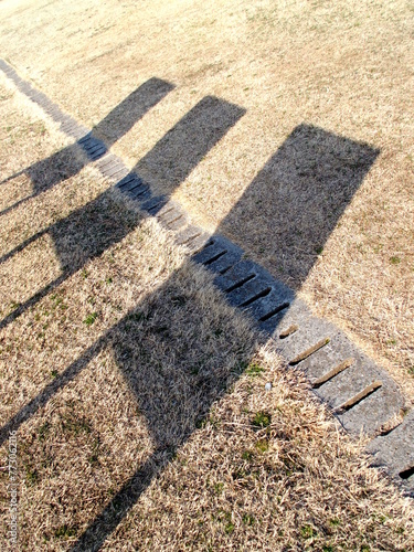 立て看板の影の映る冬の枯れ芝の江戸川土手風景