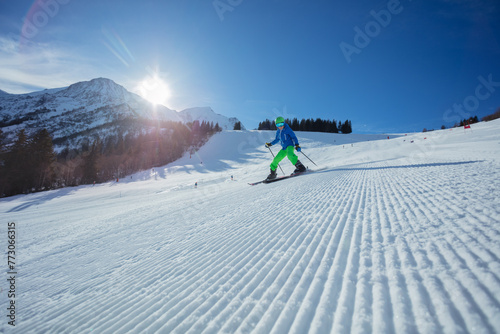 Skier kid glide on a sunny mountain slope in the morning sun