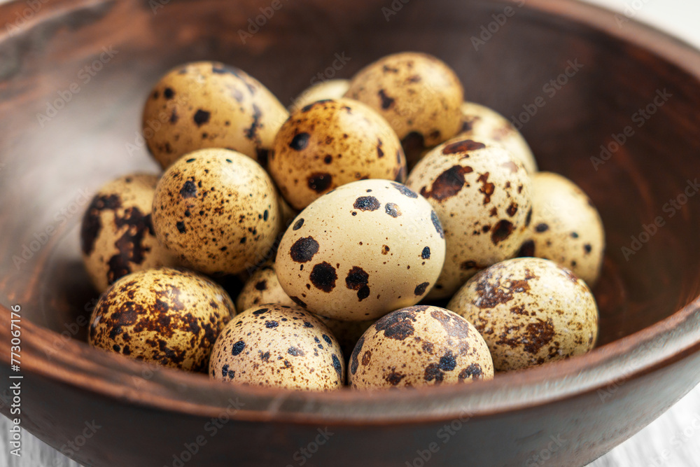 Fresh quail eggs in wooden brown bowl on a board. Easter raw foodstuff.