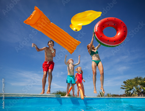 Family enjoys pool fun with floaties throw them in the air