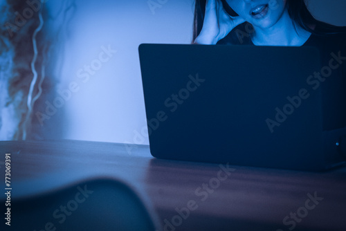 A woman relaxes and becomes aroused by watching adult content. Lonely woman watches porn films on her laptop. Concept of transgression, sex and addiction. Female enjoying spicy contents online alone photo