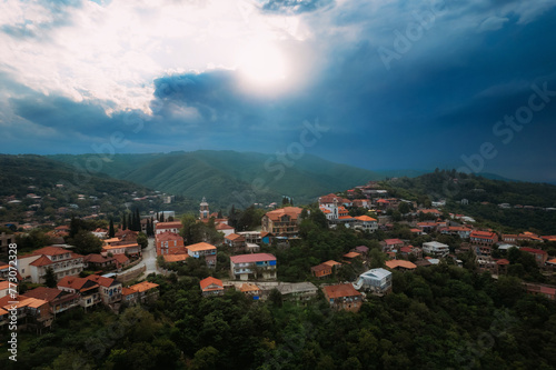 An aerial perspective of a small mountain town Sighnaghi with cloudy cumulus clouds in the atmosphere. The skyline is dotted with buildings, Kakheti, Georgia