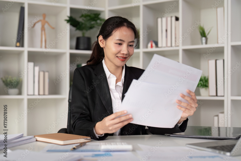 Young business woman asian or employee accounting bookkeeping documents checking financial data or marketing report working in office with laptop. Paperwork management Young business woman asian or employee accounting bookkeeping documents checking financial data or marketing report working in office with laptop. Paperwork management