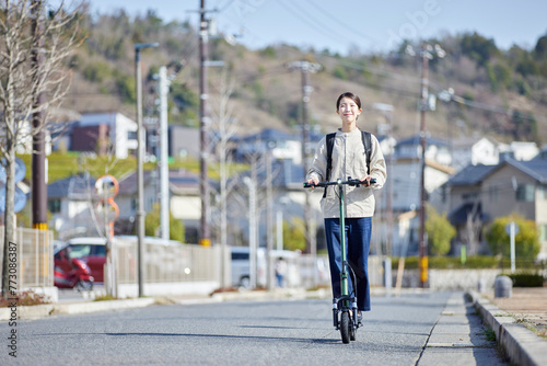 住宅街を電動キックボードで移動する日本人の女性