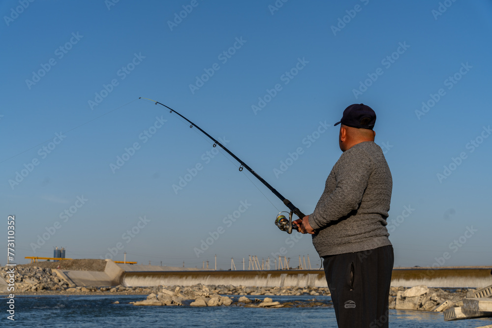 A man is fishing with a long rod and a large hook