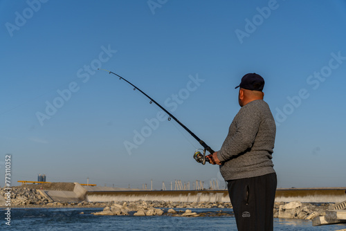 A man is fishing with a long rod and a large hook