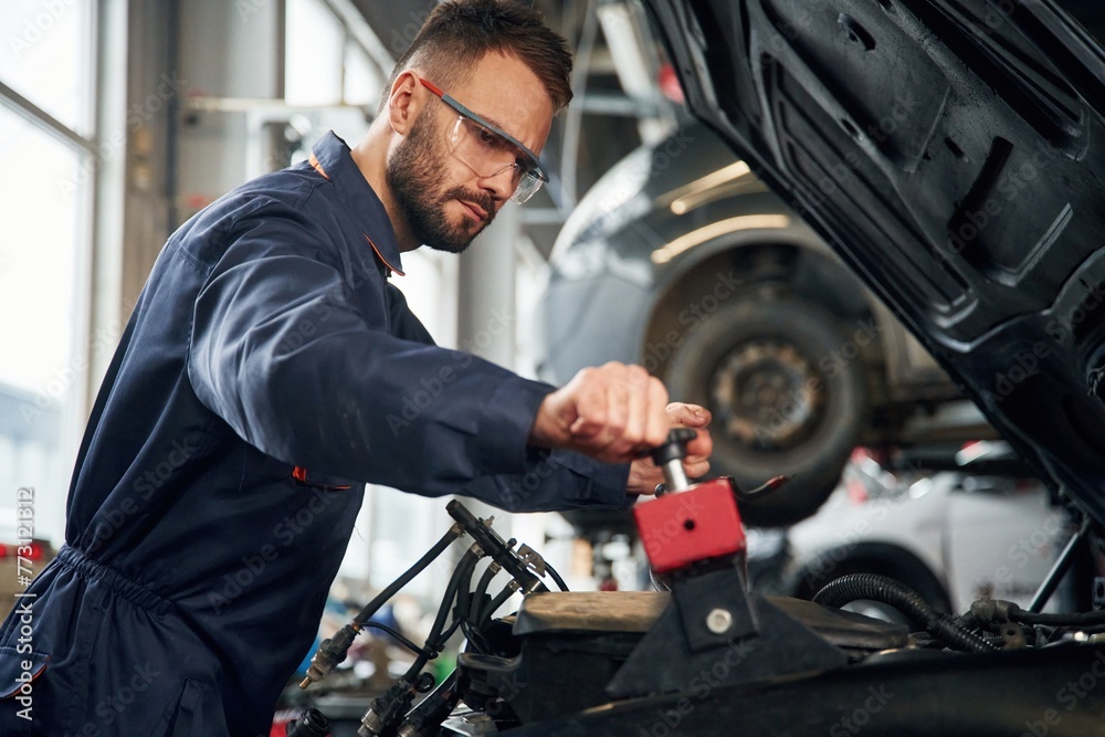 Car repairman is in the garage with automobile Car repairman is in the garage with automobile