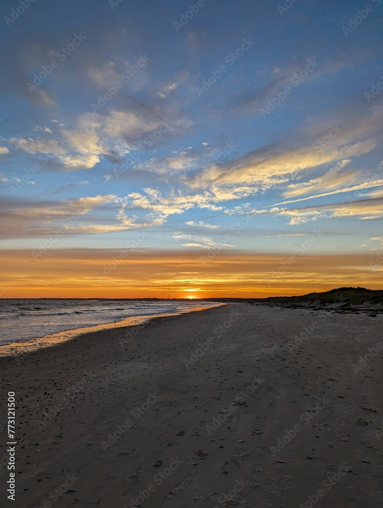 Scenic beach view of a stunning sunset with an array of clouds on the distant horizon